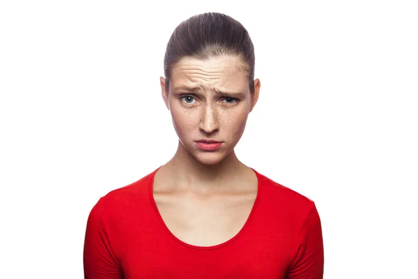 I don't know. portrait of funny confused woman in red t-shirt with freckles. looking at camera, studio shot. isolated on white background. — Stock Photo, Image