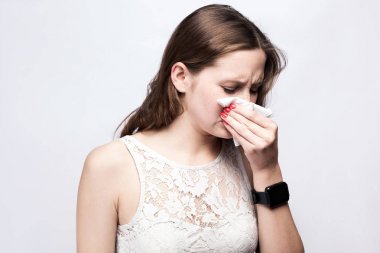 Çiller ve beyaz elbise ve gümüş gri arka plan üzerinde akıllı seyretmek ile hasta soğuk kadın portresi. Sağlık ve tıp kavramı.