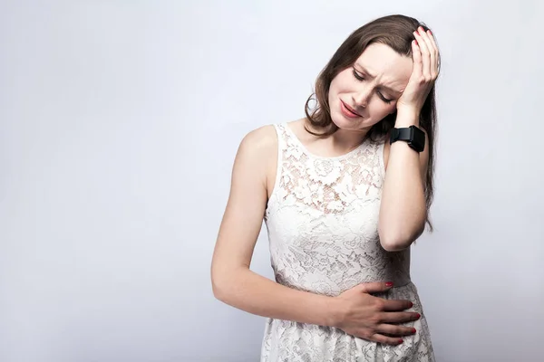 Retrato de mulher bonita com sardas e vestido branco e relógio inteligente com dor de estômago no fundo cinza prata. conceito de saúde e medicina . — Fotografia de Stock