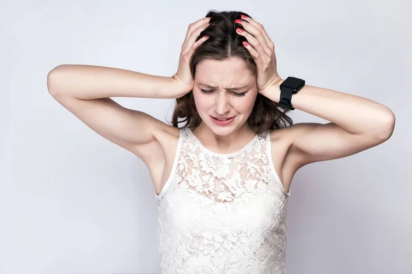 Porträt einer schönen Frau mit Sommersprossen und weißem Kleid und smarter Uhr mit Kopfschmerzen auf silbergrauem Hintergrund. Gesundheits- und Medizinkonzept. — Stockfoto