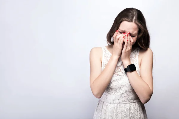 Portrait of sad, happily crying woman with freckles and white dress and smart watch on silver gray background. Salin ruang. konsep layanan kesehatan dan pengobatan . — Stok Foto