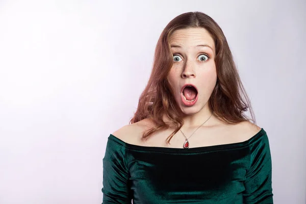 Portrait of shocked woman with freckles and classic green dress. studio shot on silver gray background. — Stock Photo, Image