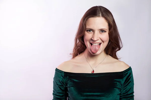 Retrato de mujer loca divertida con pecas y vestido verde clásico con lengua. estudio de tiro sobre fondo gris plateado . —  Fotos de Stock