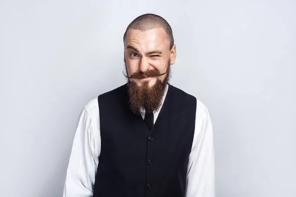 Clin d'oeil. Beau homme d'affaires avec barbe et moustache de guidon regardant caméra et clin d'oeil. plan studio, sur fond gris . — Photo