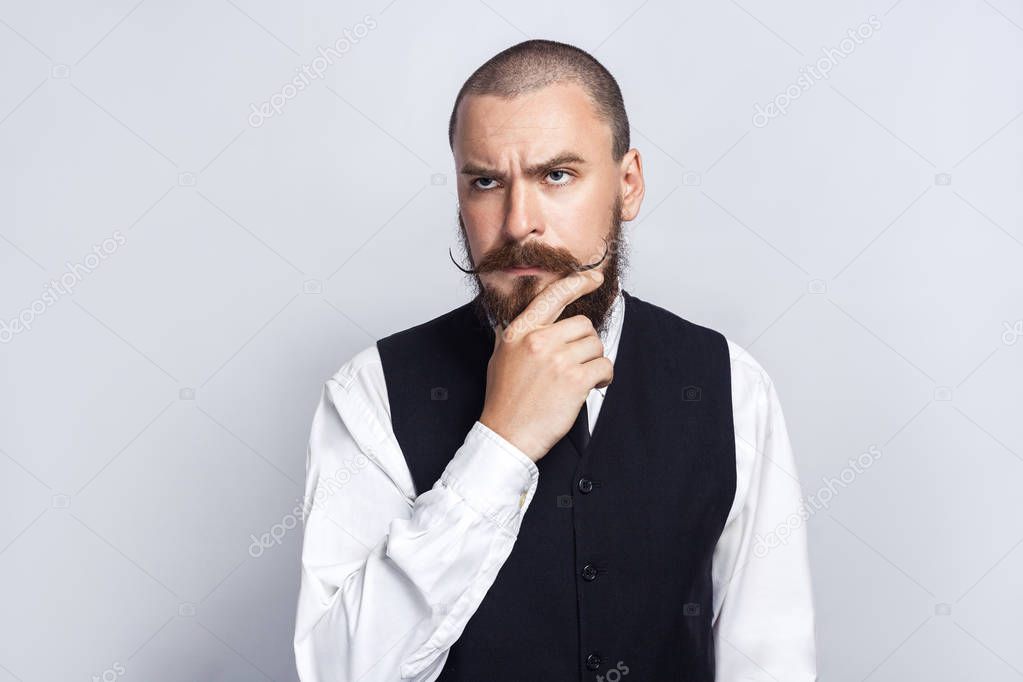 Thinking. Handsome businessman with beard and handlebar mustache looking and thinking. studio shot, on gray background.