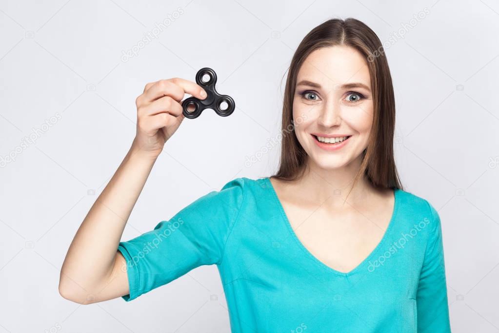 Young beautiful girl holding and playing with fidget spinner.