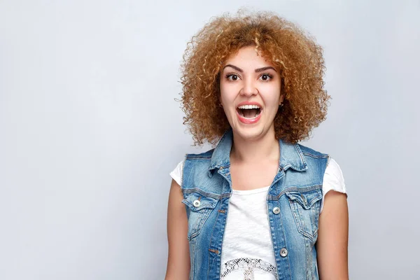 Retrato de bela menina de raça mista encaracolado surpreso em estilo casual. a olhar para a câmara. estúdio filmado em fundo cinza claro . — Fotografia de Stock