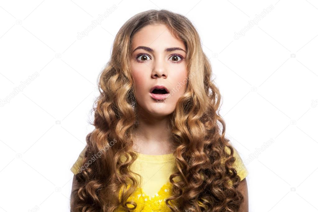 Portrait of surprised girl with wavy hairstyle and yellow t shirt. studio shot isolated on white background. 
