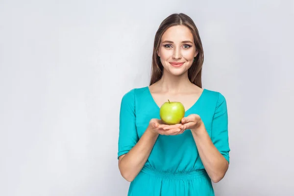 Молодая красивая женщина с веснушками и зеленым платьем держит яблоко и делится с улыбкой . — стоковое фото