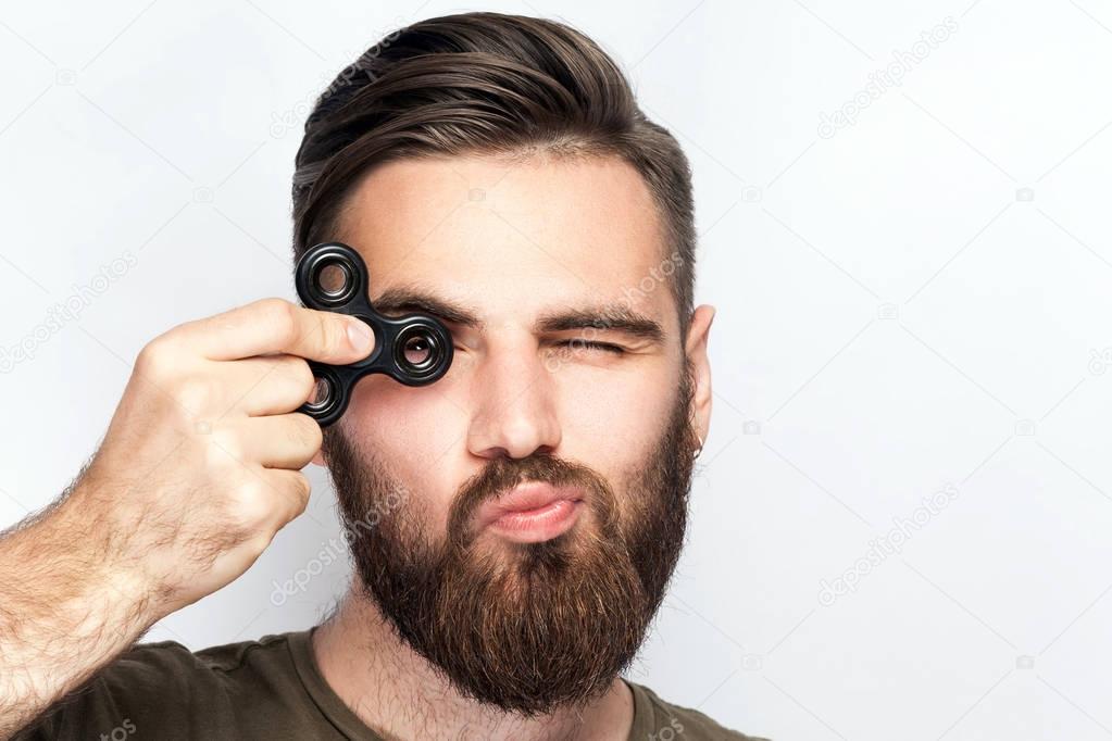 Young man holding and playing with fidget spinner. 