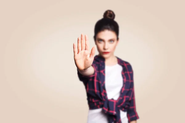 Young annoyed woman with bad attitude making stop gesture with her palm outward, saying no, expressing denial or restriction. Negative human emotions, feelings, body language. Selective focus on hand. — Stock Photo, Image