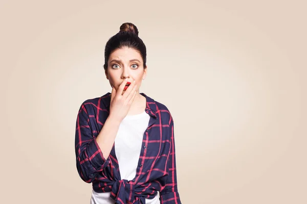 Mauvaise nouvelle. Une jeune femme effrayée lève les sourcils, garde la main sur sa joue et fixe la caméra, après avoir choqué le regard effrayé. studio tourné sur fond beige . — Photo