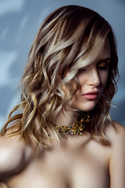 Portrait de beauté de modèle de mode beautful avec maquillage, coiffure vawy colorée et accessoires sur son cou. studio tourné sur fond bleu . — Photo