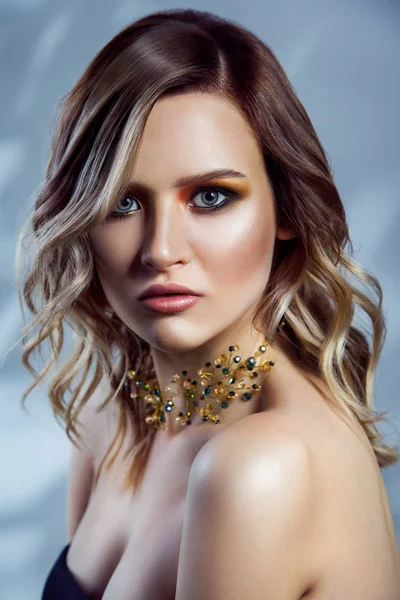 Portret van de schoonheid van beautful mannequin met gekleurde vawy kapsel, make-up en accessoires op haar nek. studio opname op blauwe achtergrond. — Stockfoto