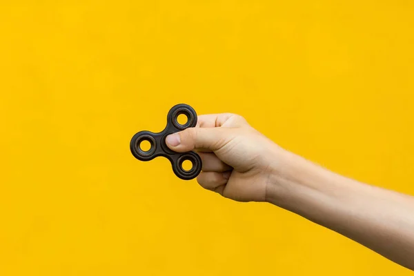 Menino com fidget spinner no fundo amarelo . — Fotografia de Stock