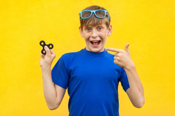 Niño con fidget spinner sobre fondo amarillo . —  Fotos de Stock