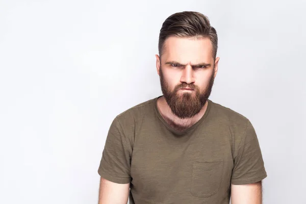 Portrait d'homme barbu triste en colère avec t-shirt vert foncé sur fond gris clair. plan studio . — Photo