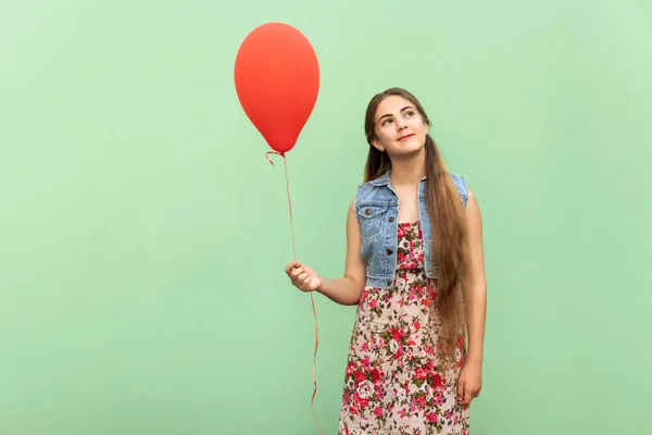 A bela adolescente loira sonhando, com balão vermelho em um fundo verde claro. Estúdio isolado tiro — Fotografia de Stock