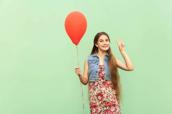 Signo V! A bela adolescente loira com balões vermelhos em um fundo verde. Estúdio isolado tiro — Fotografia de Stock