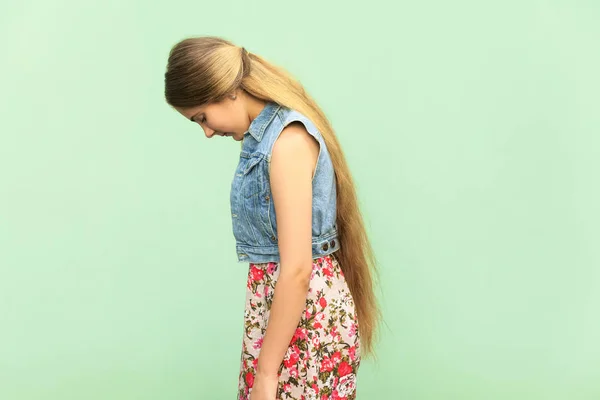 Sidovy av ledsen tonåring flicka, straffas ensam på grön vägg. Inomhus studio shoot — Stockfoto