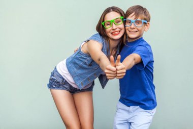 Aile, duygu ve duygu. Ablası ve kardeşi mavi arka plan üzerinde birlikte poz, dişlek gülümseme ve başparmak ile kameraya bakarak, çilli. Stüdyo vurdu