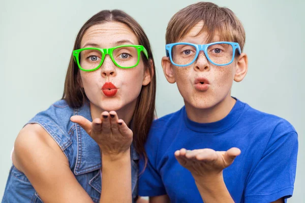 Young sister and brother with freckles on their faces, posing over light blue background together, looking at camera and sending kisses. Studio shot — Stock Photo, Image