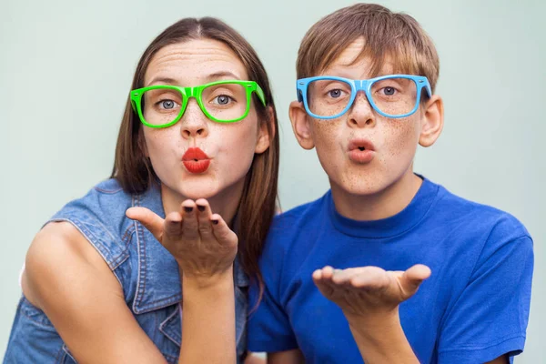 Hermana joven y hermano con pecas en la cara, posando sobre fondo azul claro juntos, mirando a la cámara y enviando besos. Captura de estudio —  Fotos de Stock