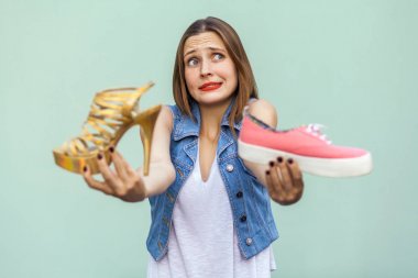 The beautiful girl with freckles in mall got choosing sneakers or handsome shoes, thinking and looking up.  clipart