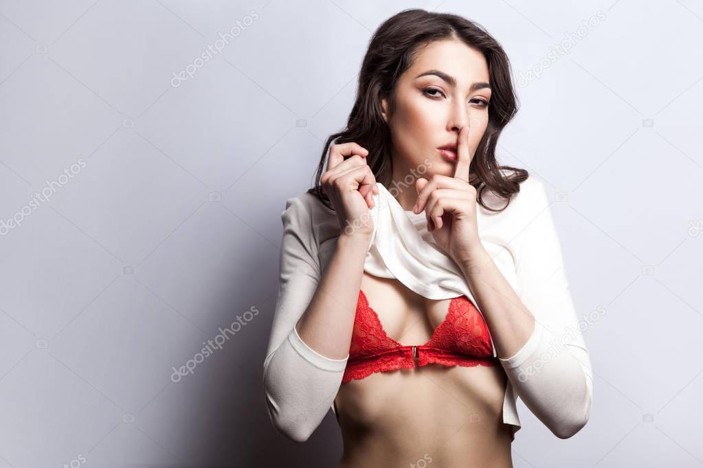 Secret between us, do not tell anyone. Sexy young fashion model undressing and looking at camera