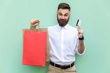 Kredi kartı ile online alışveriş veya bankacılık için genç yetişkin iş adamı. Kredi kartı üzerinde elele ve kamera ve gülümseme bakarak. Kapalı, stüdyo vurdu. Açık yeşil arka planı