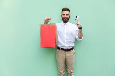 Online alışveriş için kredi kartı ile iş adamı. Kamera ve dişlek gülümseme bakarak. Kapalı, atış, studio yeşil arka plan
