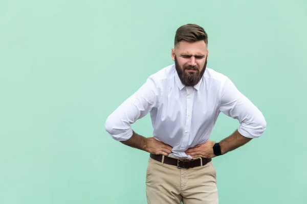 Špatné emoce a pocity, bolesti. Mladý muži, zažívá bolest žaludku, izolované na světle zeleném pozadí. Indoor, studio zastřelil — Stock fotografie