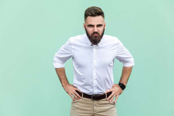 Плохие эмоции и чувства. Мужчина, злой взгляд на камеру на светло-зеленом фоне в студийной съемке
.