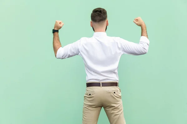 Aufgeregter Geschäftsmann feiert einen Karriereerfolg. Rückansicht eines jungen erwachsenen Geschäftsmannes auf hellgrünem Hintergrund. Innenaufnahmen, Studioaufnahmen — Stockfoto