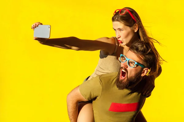 A cuestas. amigos divertidos macking selfie sobre fondo amarillo y muecas. Captura de estudio — Foto de Stock