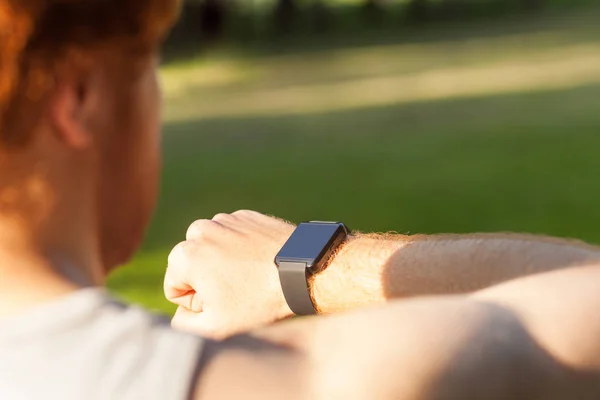 Roodharige atleet, kijken in slimme wath of fitness tracker — Stockfoto