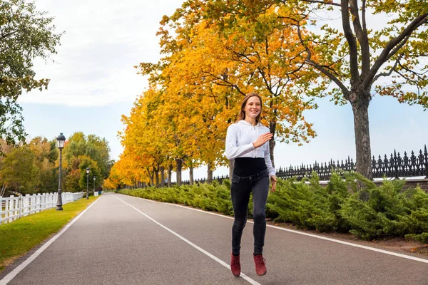 Close up. Healthy woman jogging in autumn park.