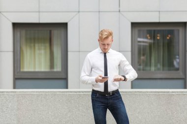 Endişeli işadamı son tarih ile ilgili bir sorun var. Akıllı telefon tutarak ve ekrana bakarak.