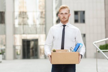 Unhappy bearded business man going out with cardboard, looking at camera and feeling looser. clipart