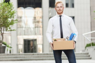 Gülümseyen ve kameraya bakarak yeni işin için iyi giyimli genç yetişkin iş adamı,