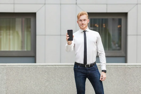 Success business man showing new smart phone and looking at camera. — Stock Photo, Image