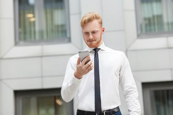 Close up ginger young adult businessman. working at mobile phone and looking at screen smart phone. — Stock Photo, Image