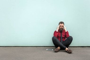 Genç Yetişkin sakallı iş adamı yere oturur.