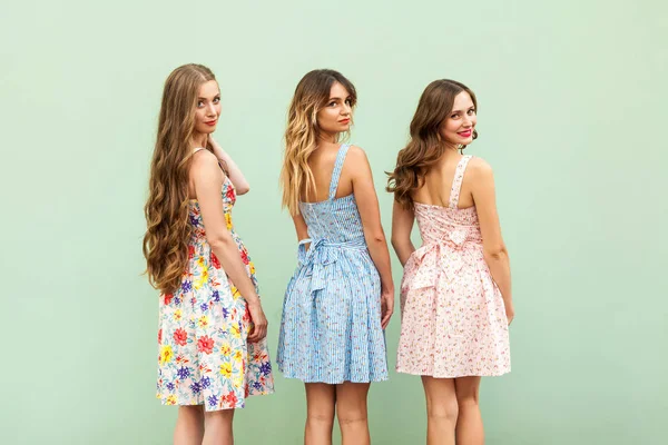 Tři mladé kamarádky v roztomilé šaty obrátil přes rameno — Stock fotografie