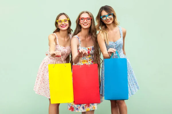 Porträtt av tre ganska glada tjejer med paket med nya kläder. — Stockfoto