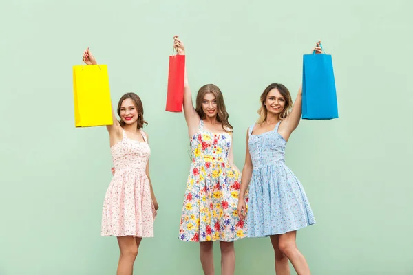 Ung vuxen tjej i klänning, visar hennes väskor efter shopping. Upp med händerna och hålla hennes färgglada väskor. — Stockfoto