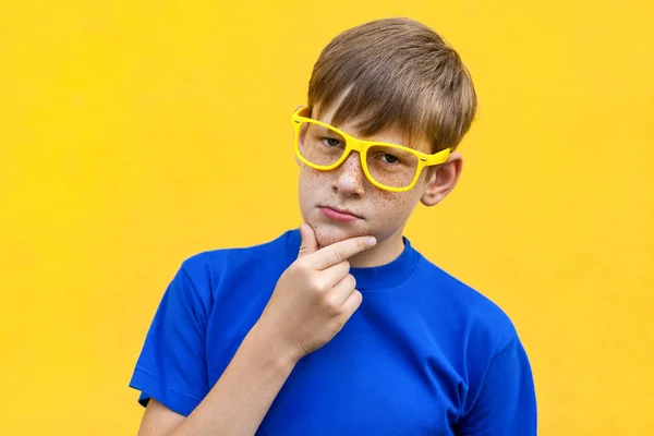 Serious freckled boy looking at camera, touching chin and thinki — Stock Photo, Image