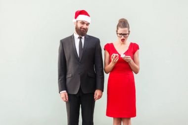 Proud man in christmas cap looking a gift. Frustrated woman hold clipart