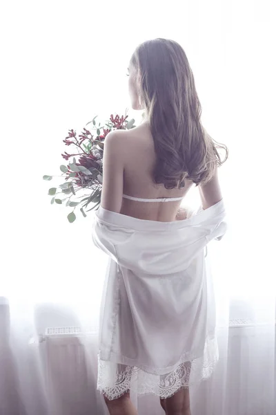 Vista trasera para chica sexy en camisón, sosteniendo flores, de pie ne —  Fotos de Stock