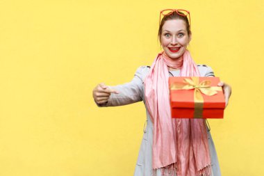 Hediye kutusu üzerinde parmak işaret ve cam arayan genç yetişkin kadın